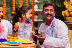 Young girl and her grandfather apply colored powder to celebrate Holi.
