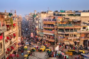 Aerial view of a busy city street in India with many pedestrians and pedicabs.