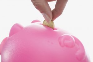 Close up of woman feeding piggy bank