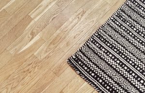Stylish black and white rug on wooden floor