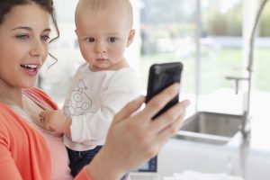 Mother holding baby and using cell phone