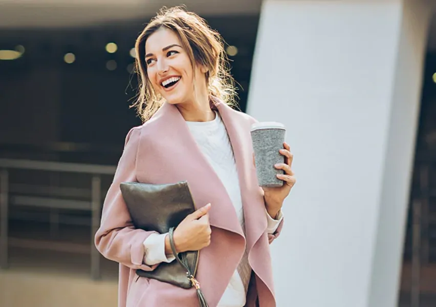 smiling_woman_holds_clutch_and_drinking_coffee
