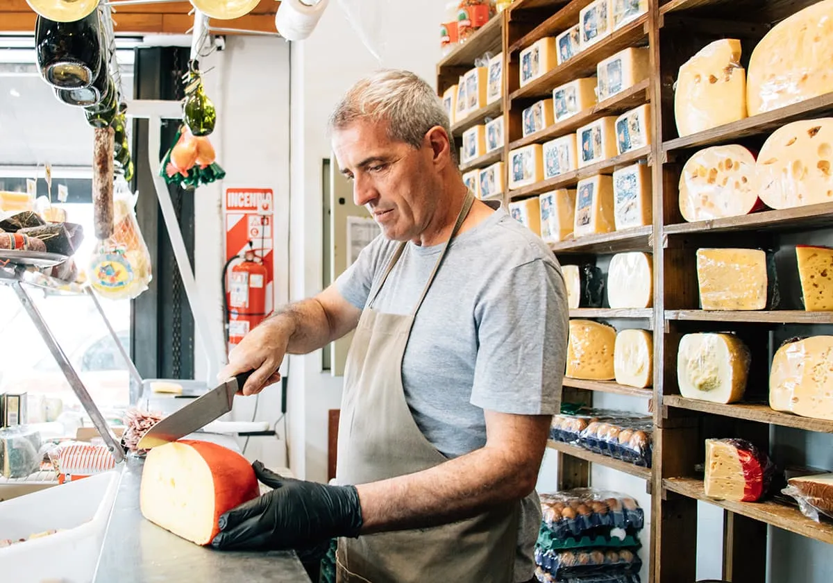 Man cutting cheese in a specialised shop