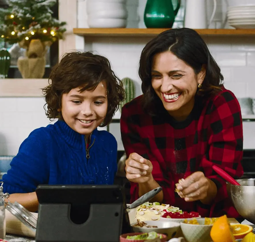 Kid and woman smiling and looking at tablet screen