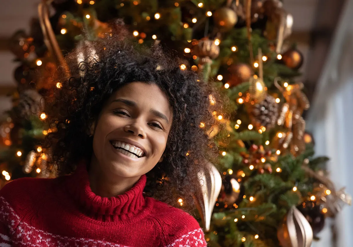 Woman smiling with a christmas tree behind