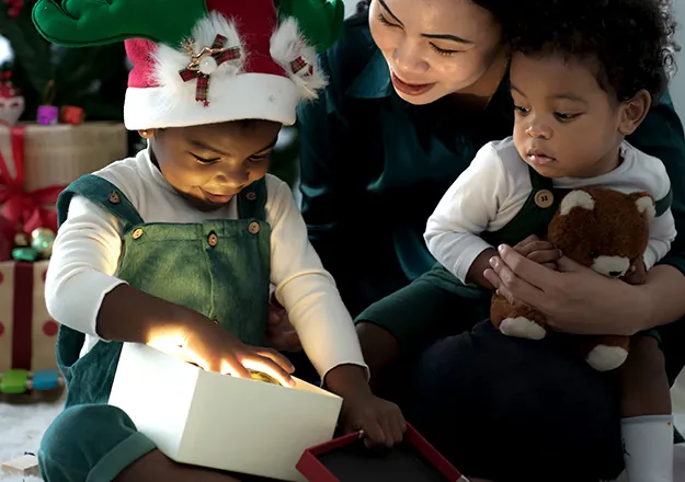 Young girl opening Christmas presents with two toddlers